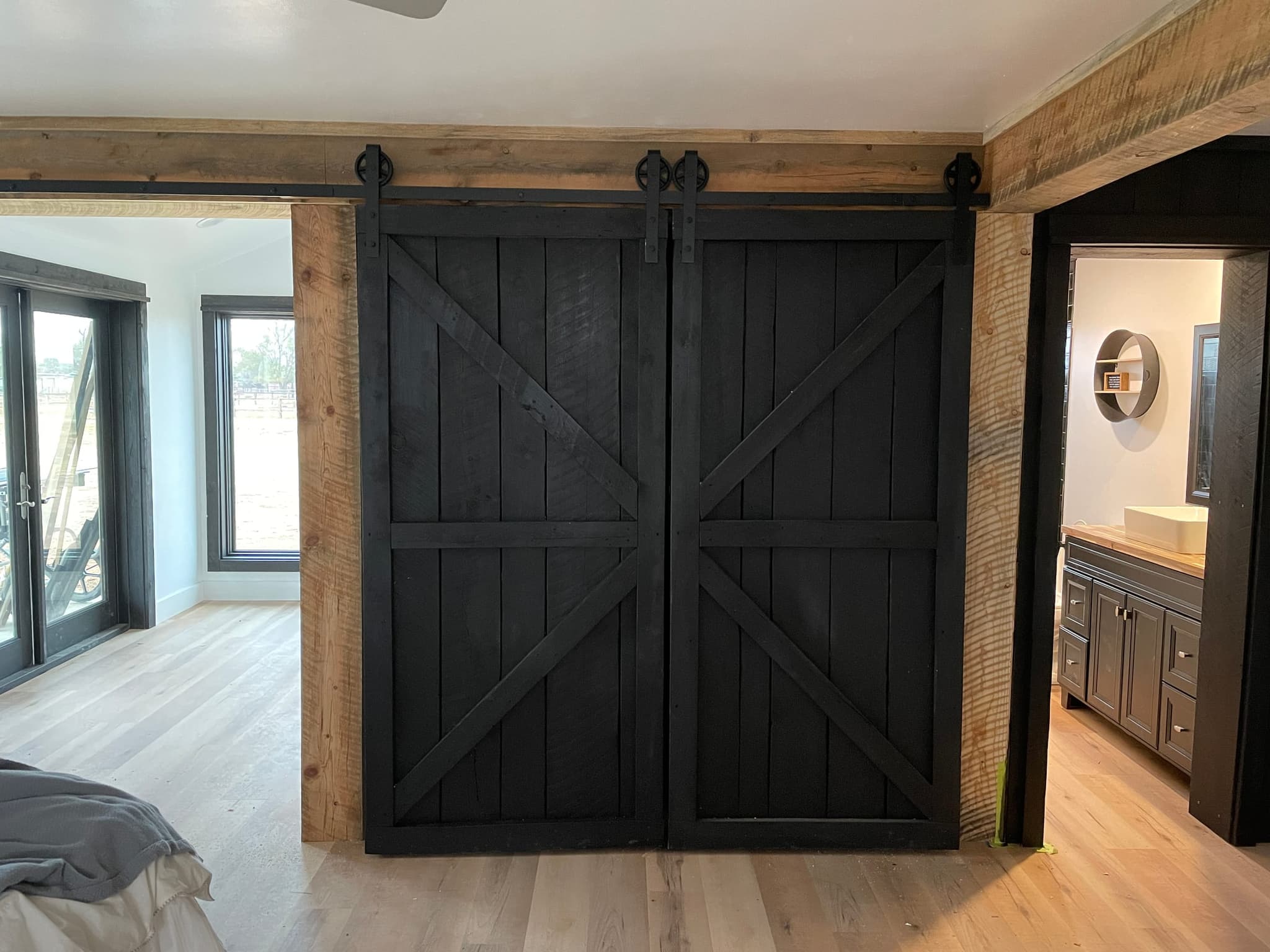 Hand-built sliding barn doors on a rustic timber frame in a master bedroom