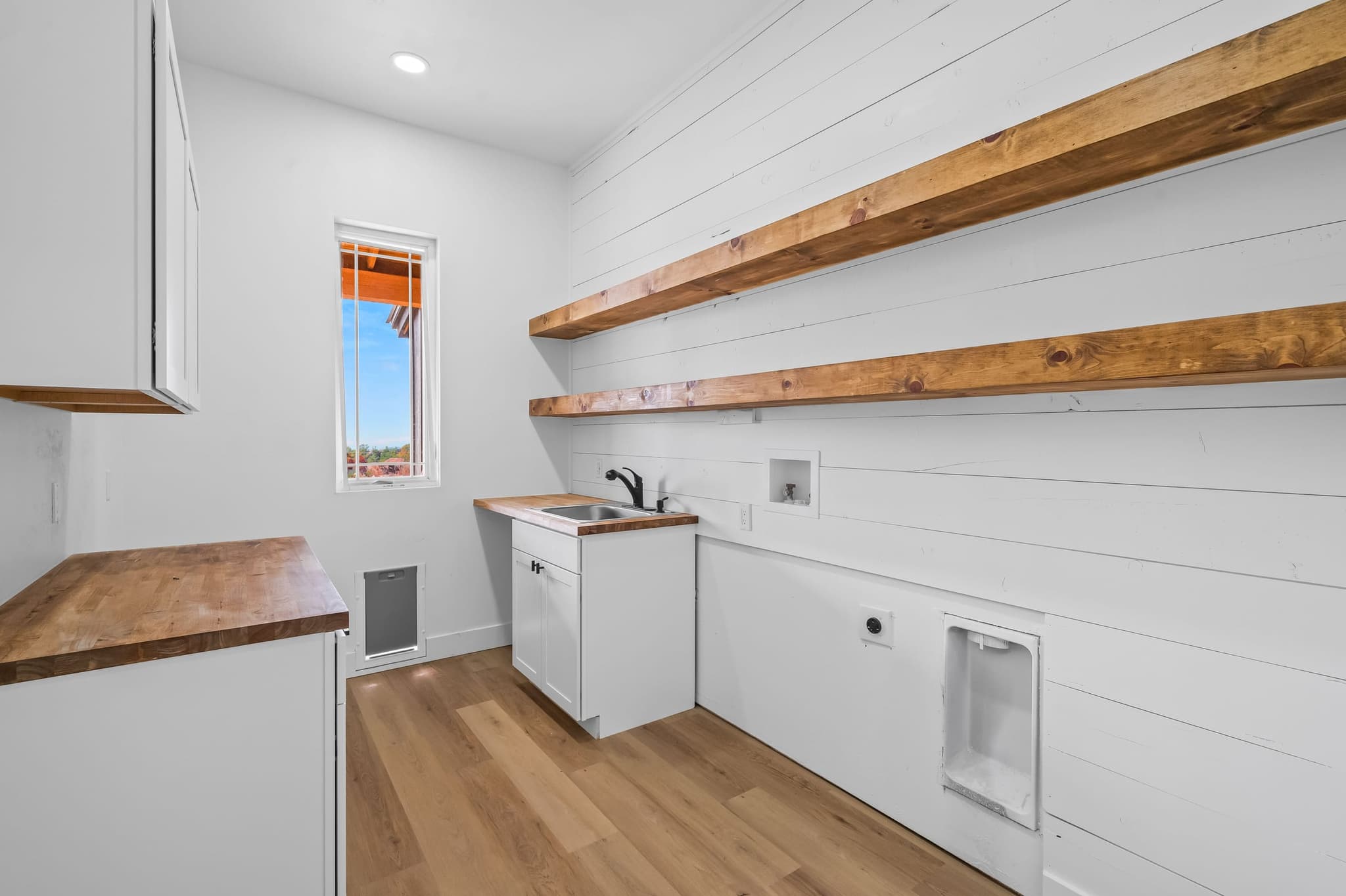Laundry room with a butcher-block counter, sink and dog door