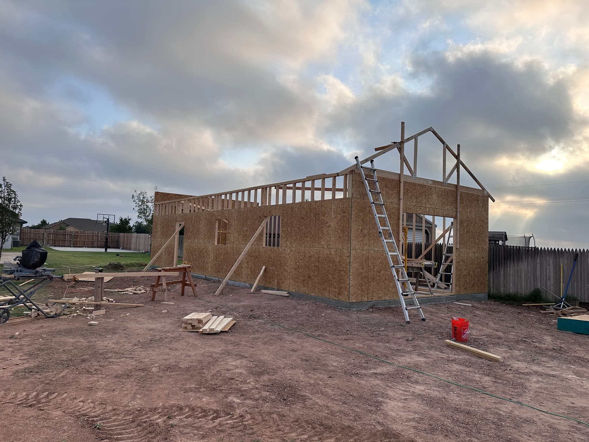 Shop walls up and sheathed with trusses going on at dusk