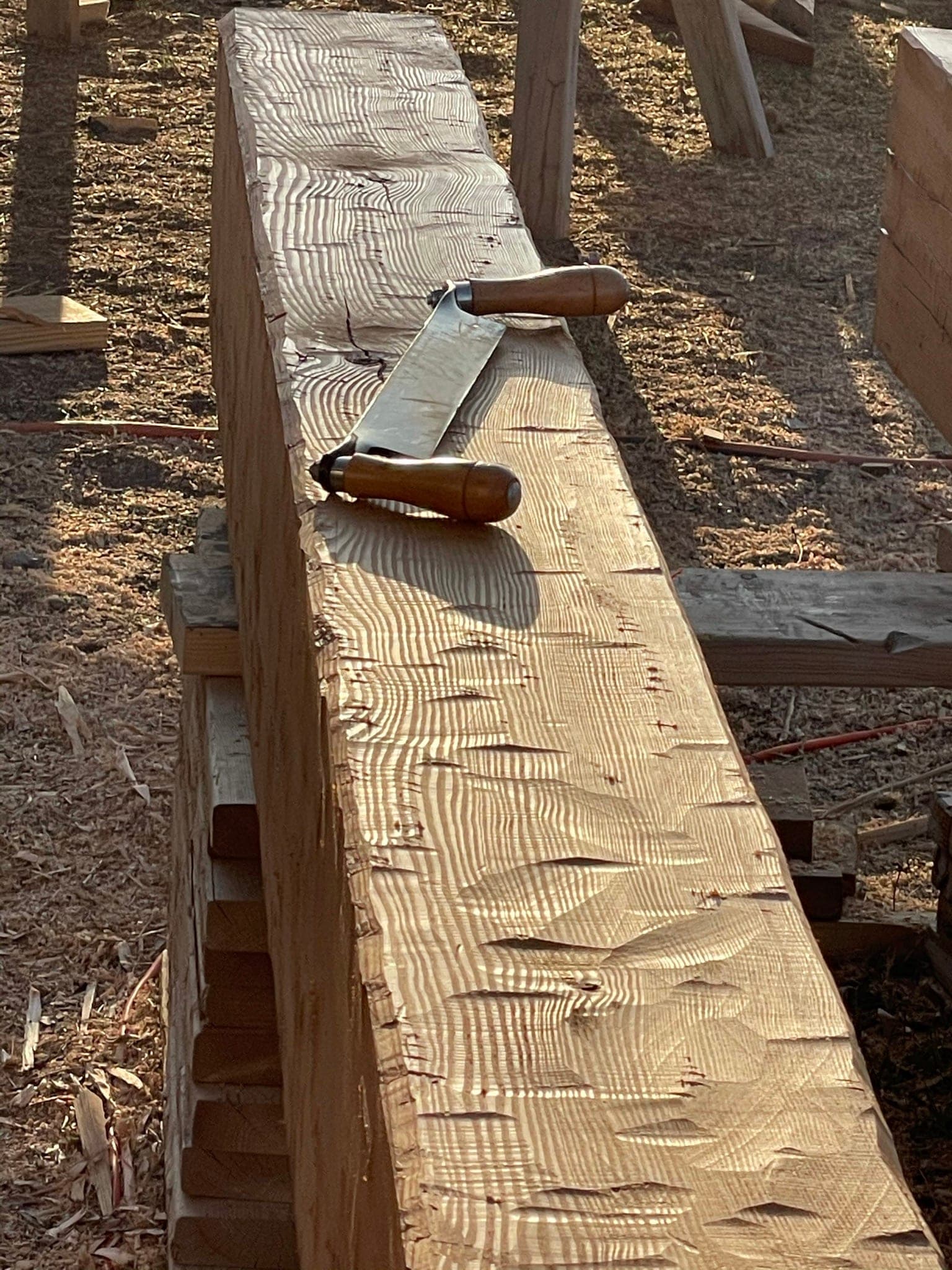 Hewing a porch beam by hand with a drawknife