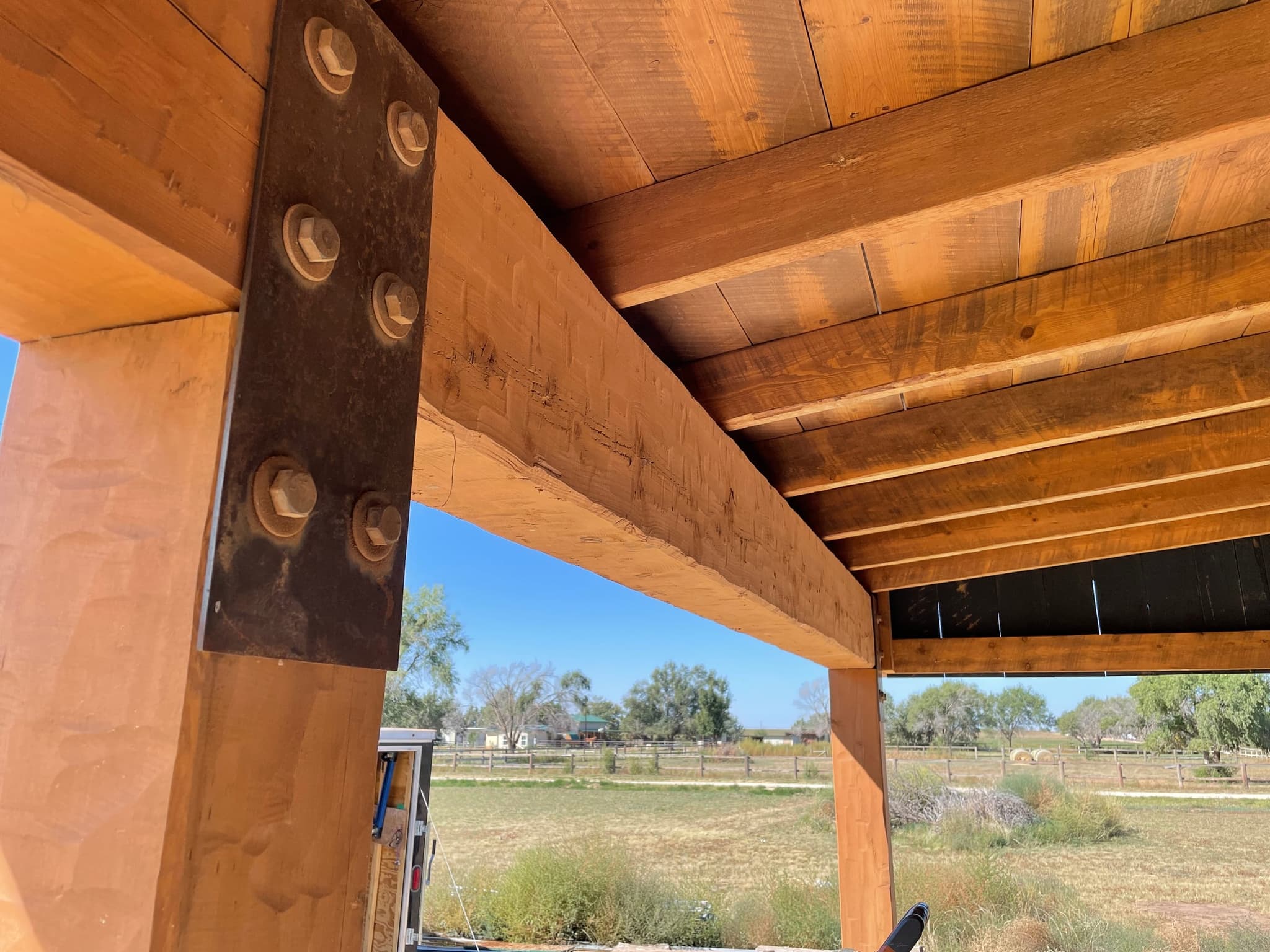 Finished timber frame porch with hand-hewn beams on steel plates